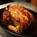 Perfectly Roasted Whole Chicken with crispy skin in a cast iron pan.
