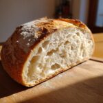 A loaf of sourdough bread made with active sourdough starter, showing a light and airy crumb.