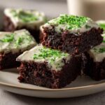 A stack of delicious St Patrick’s Day treats: lucky brownies with white frosting and green sprinkles.