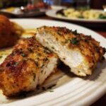 Close-up of Texas Roadhouse Herb Crusted Chicken cut open, showing the juicy interior and crispy herb crust.