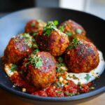 A plate of delicious Easy Vegetarian Lentil Meatballs served with sauce and herbs.