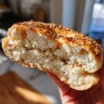 Close-up of a bagel filled with a creamy filling, potentially related to creamy blueberry cheesecake protein bites.