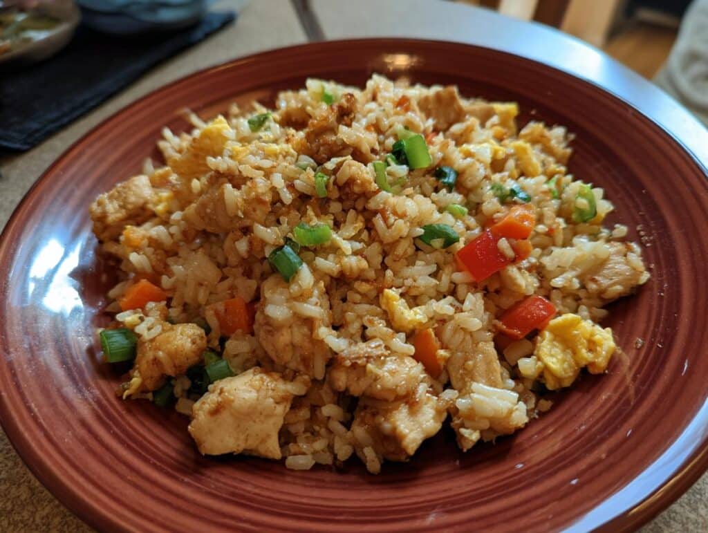 A plate of chicken fried rice with vegetables. Not related to blueberry muffin protein bites.