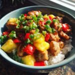 A vibrant chicken rice bowls with pineapple, red peppers, and green onions in a blue bowl.