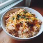 Bowl of Mexican chicken rice crock pot, topped with melted cheese and fresh parsley.