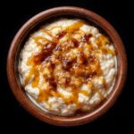 Overhead view of easy Mexican rice pudding recipe in a wooden bowl, drizzled with caramel.