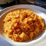 A serving of flavorful Mexican rice recipe slow cooker, garnished with herbs and visible onion pieces.