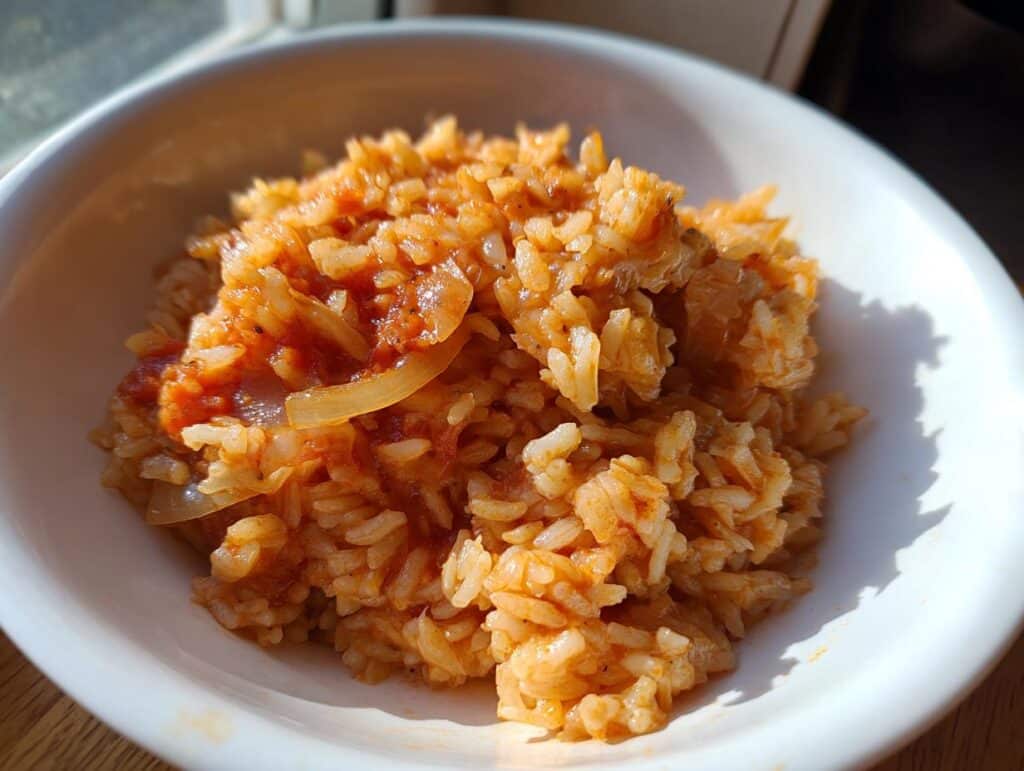 Bowl of homemade Mexican rice recipe slow cooker, featuring rice, tomatoes, and onions.