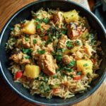 Bowl of pineapple chicken rice easy recipe, garnished with fresh herbs and colorful vegetables.