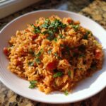 A serving of rice cooker Mexican rice with Rotel, garnished with fresh parsley, on a white plate.