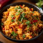 Close-up of rice in a bowl, mixed with red peppers and topped with fresh cilantro.