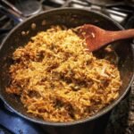 Savory rice dish in a pan with a wooden spoon. Not related to baked blueberry cottage cheese breakfast bowls.