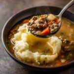 Close-up of Shepherds Pie Soup being served with a spoonful of beef, vegetables, and mashed potatoes.